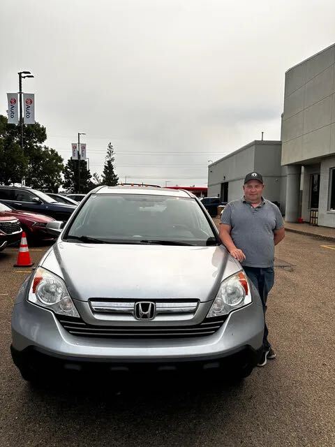 Proud car buyer standing beside silver Honda SUV