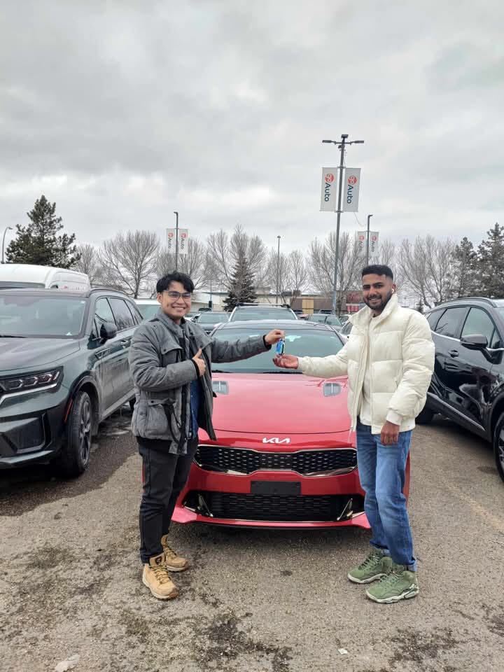 Happy customer receiving keys to red car