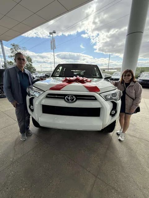 Couple taking delivery of white Toyota SUV with big red bow