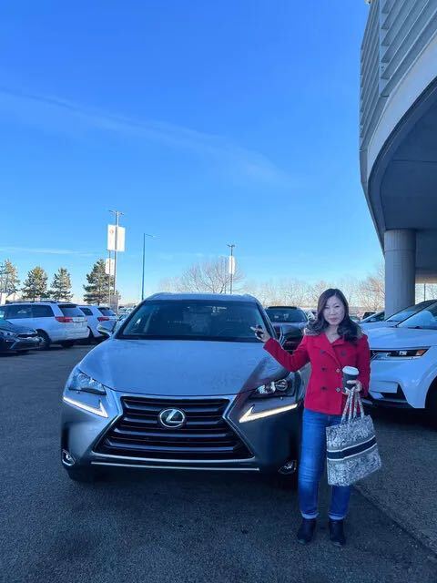 Happy client in red coat standing with silver Lexus SUV