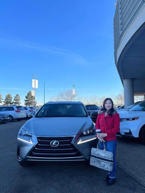 Happy customer standing beside grey Lexus SUV