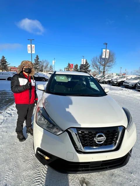 Customer with thumbs up beside white Nissan SUV in winter