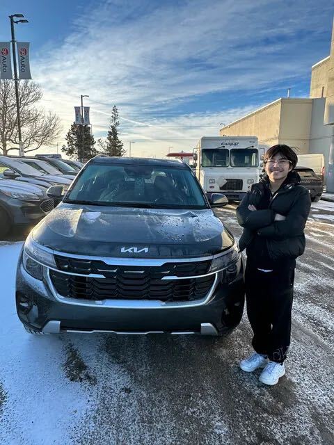 Customer standing beside dark grey Kia SUV