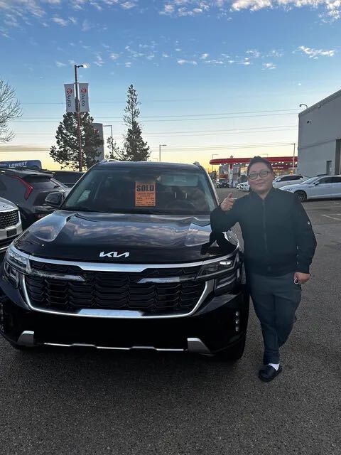 Happy customer giving thumbs up with black Kia SUV