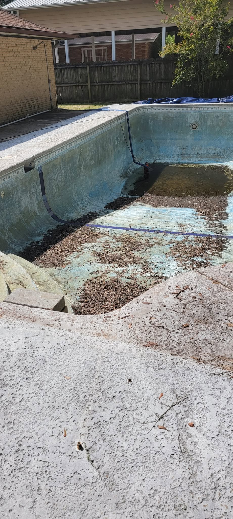 Drained pool before deep cleaning with leaf buildup