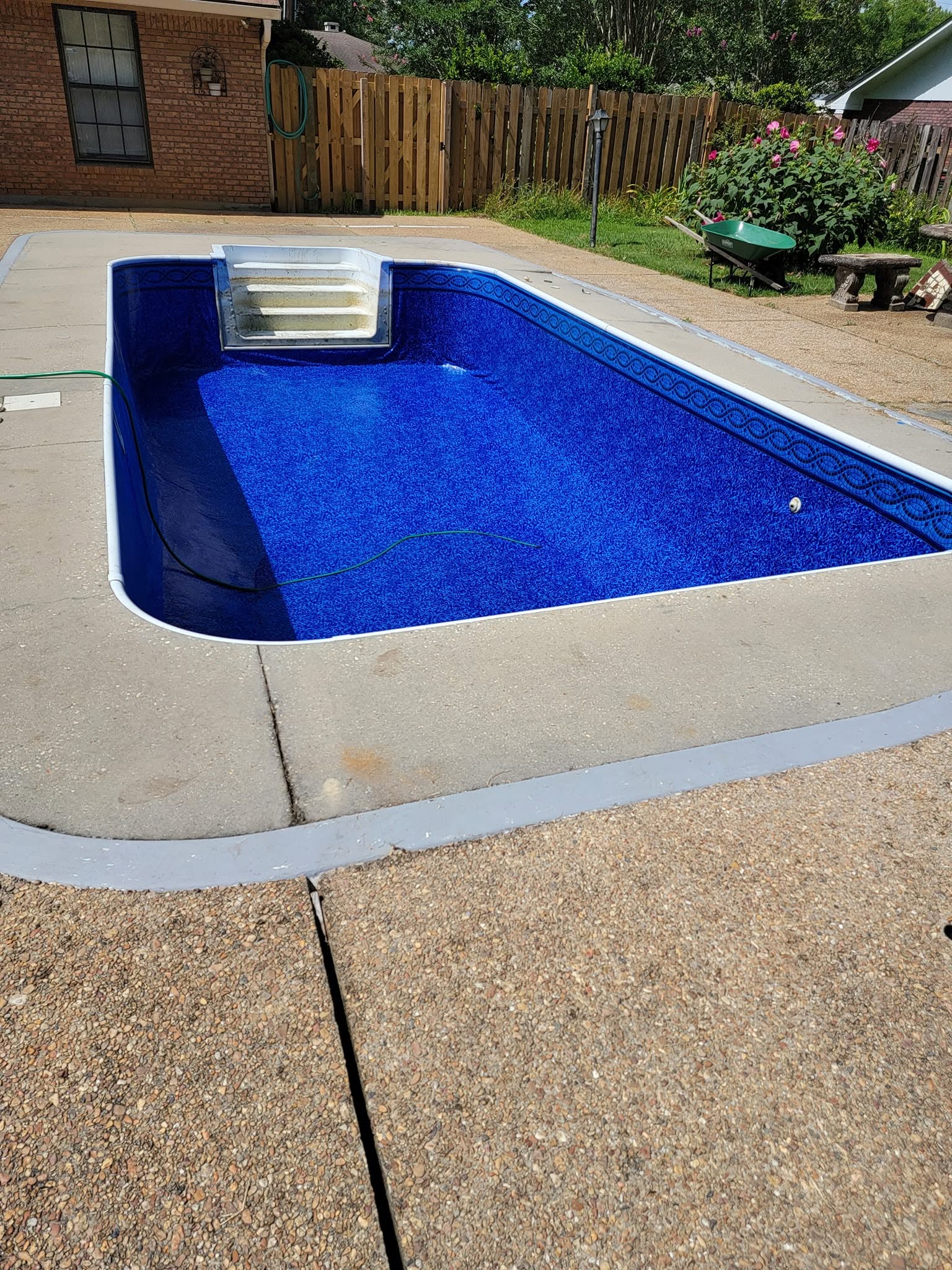 In-ground swimming pool with new deep blue patterned liner along patio