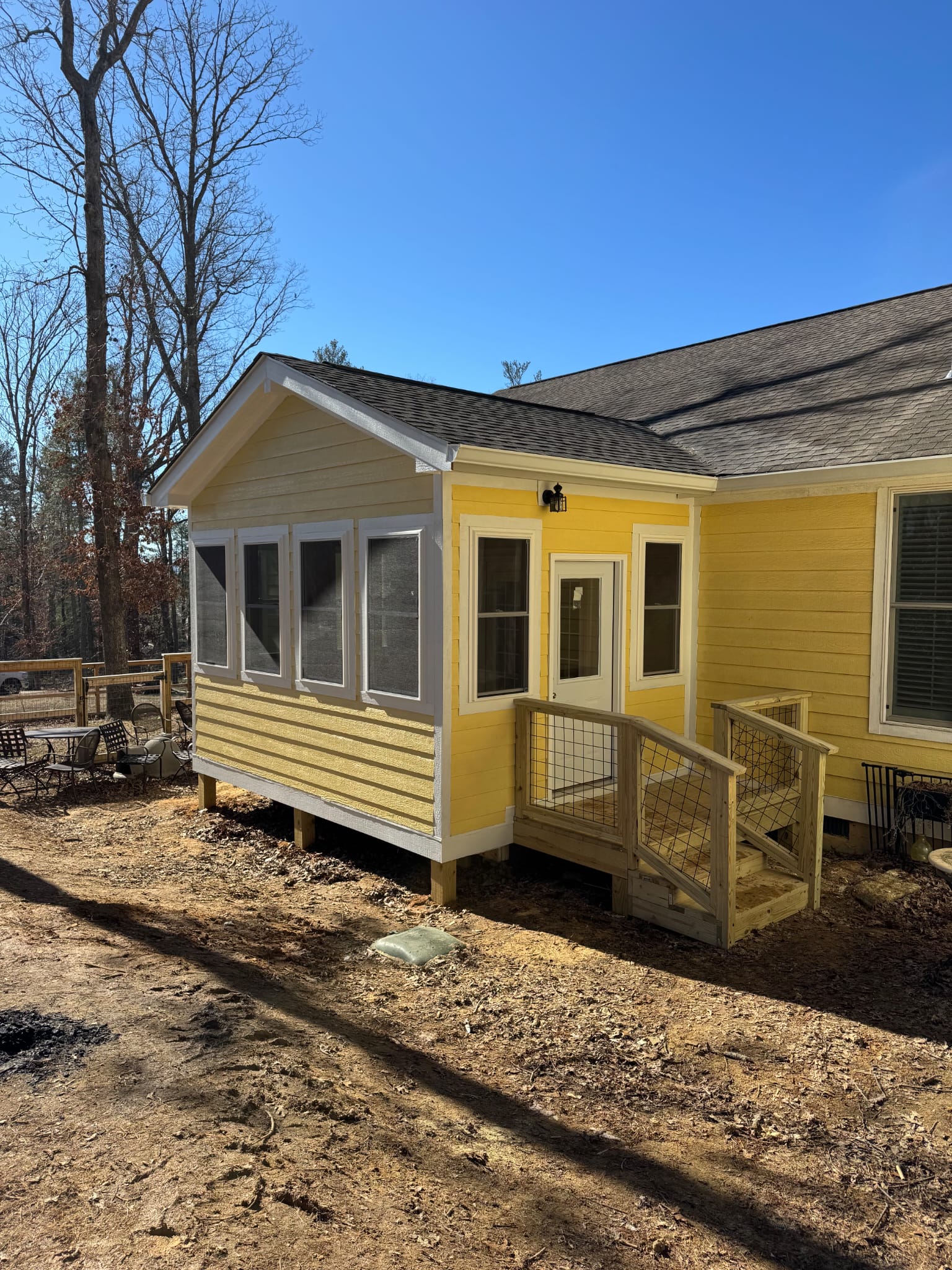 Custom home build with yellow siding, custom screened sunroom, and wood entry porch built by Southern Forge Construction in North Carolina