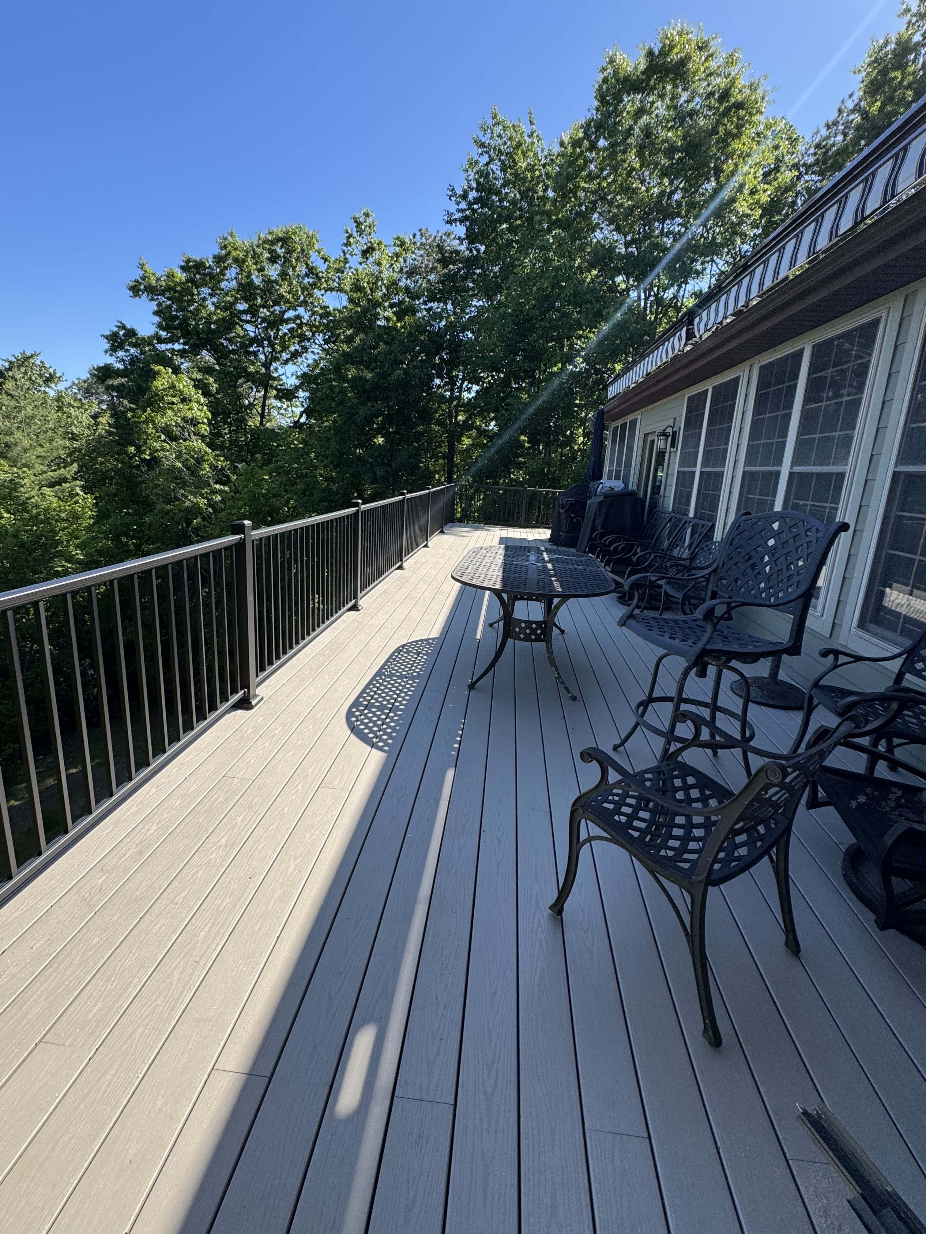 Expansive outdoor composite dining deck with modern black railings and wooded forest views