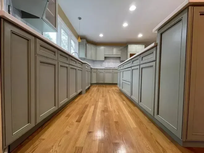 Kitchen with light-green cabinets, white countertops, and hardwood floors.