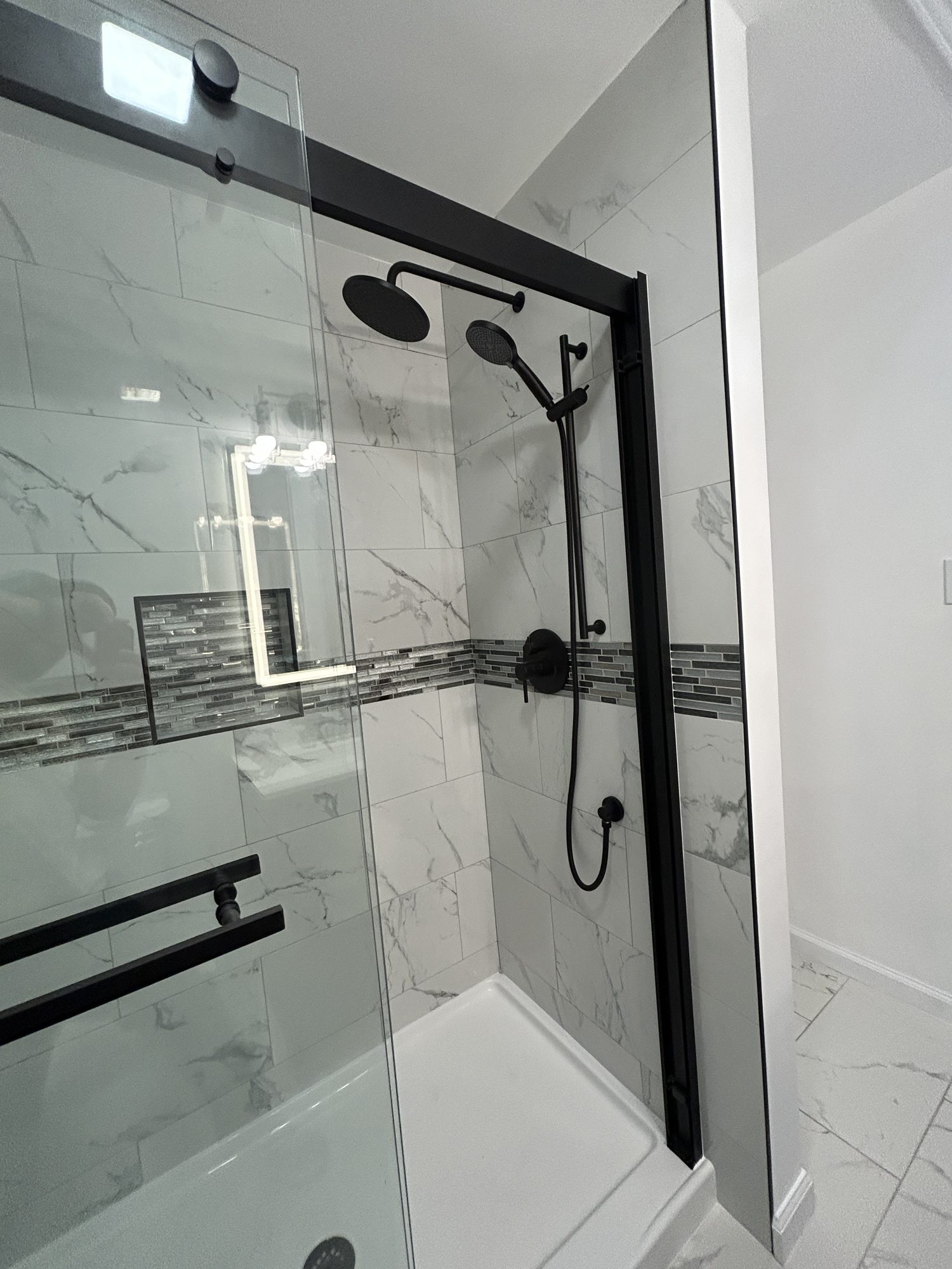 Sliding black frame glass shower door with dual matte black shower heads and marbled tile, Reno, NV