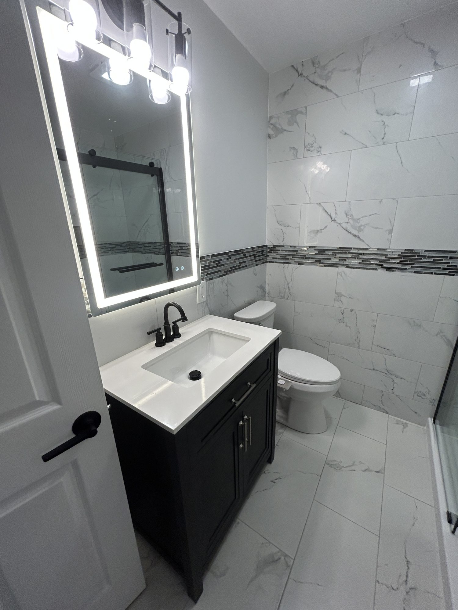 Navy vanity with white quartz top, matte black faucet, and backlit LED mirror, Reno, NV