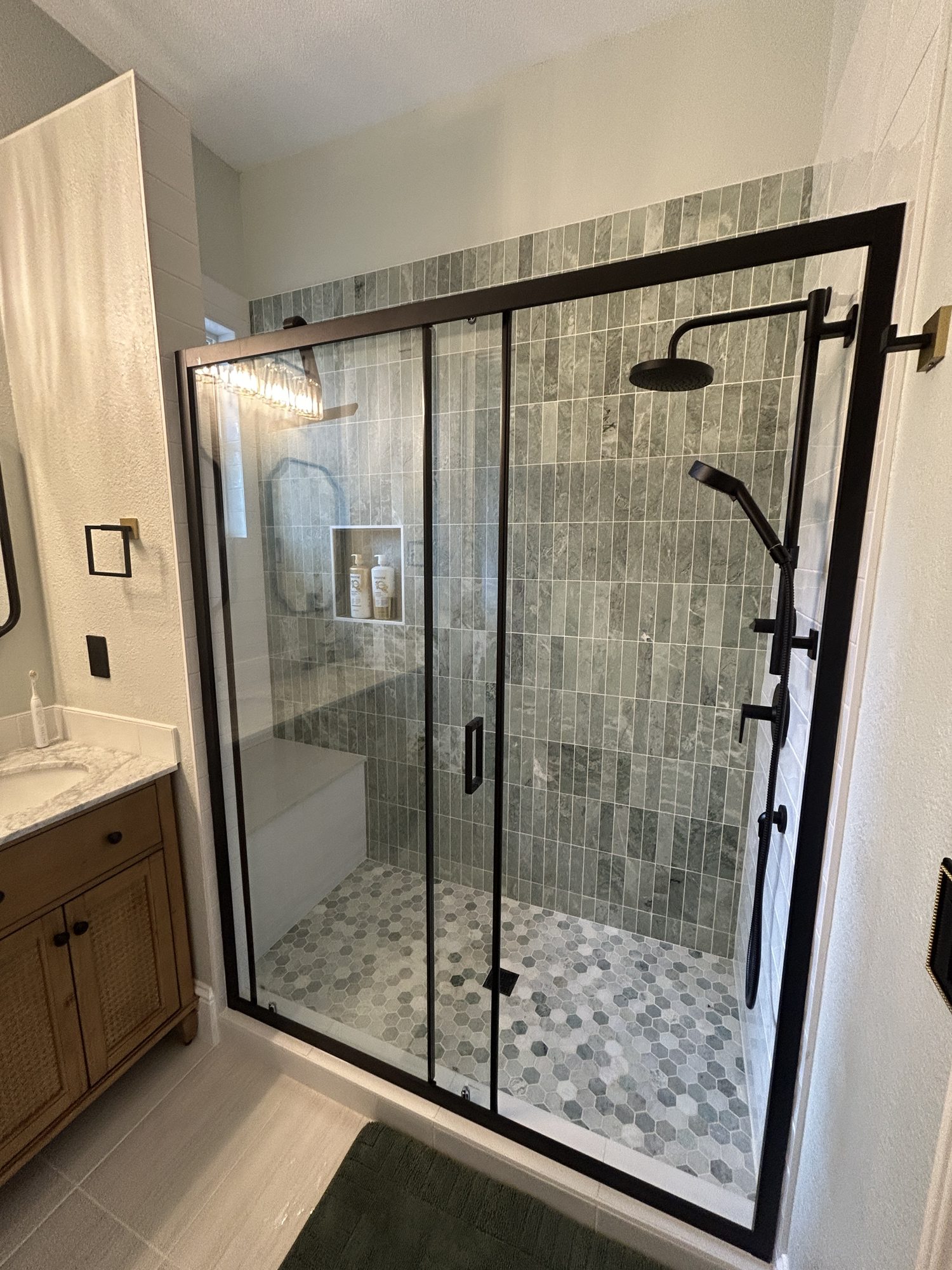 Remodeled walk-in shower with green stacked marble tile and black-frame glass, Reno, NV
