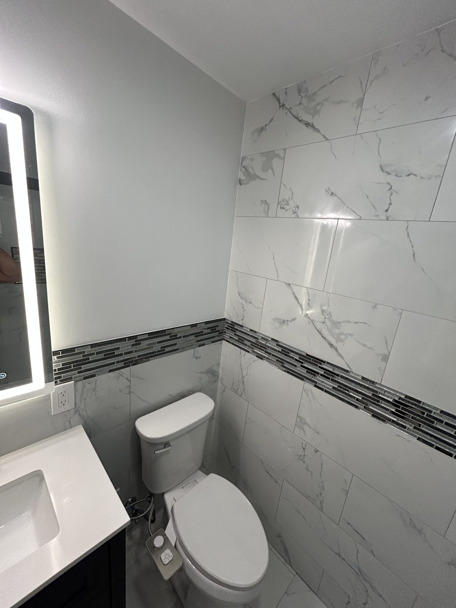 Marbled porcelain wainscoting with glass mosaic accent band and toilet niche detail, Reno, NV
