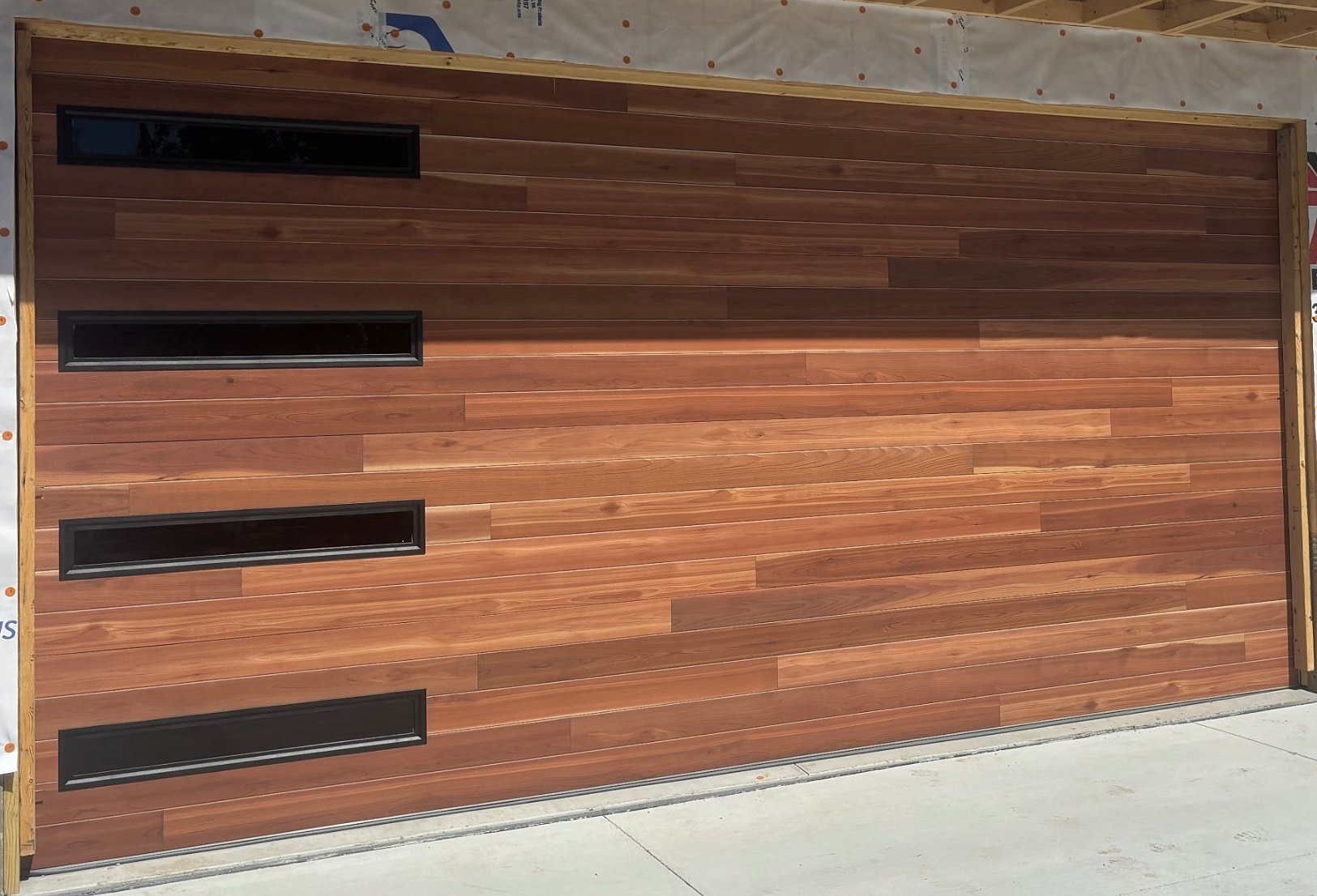 Modern wood grain garage door with black window strips installed by Nelson Garage Solutions