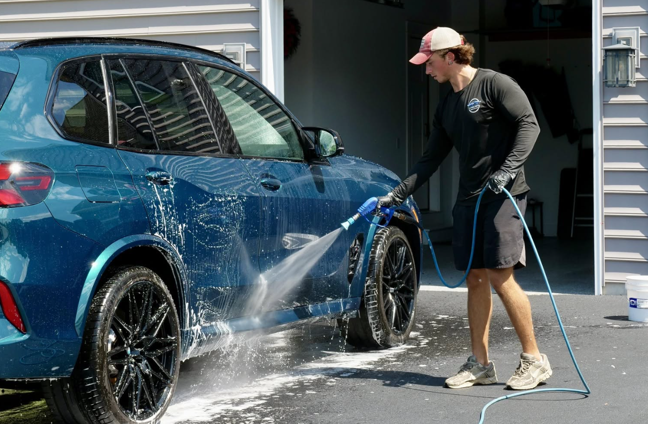 David from The Final Detail pressure washing a blue SUV in a customer driveway