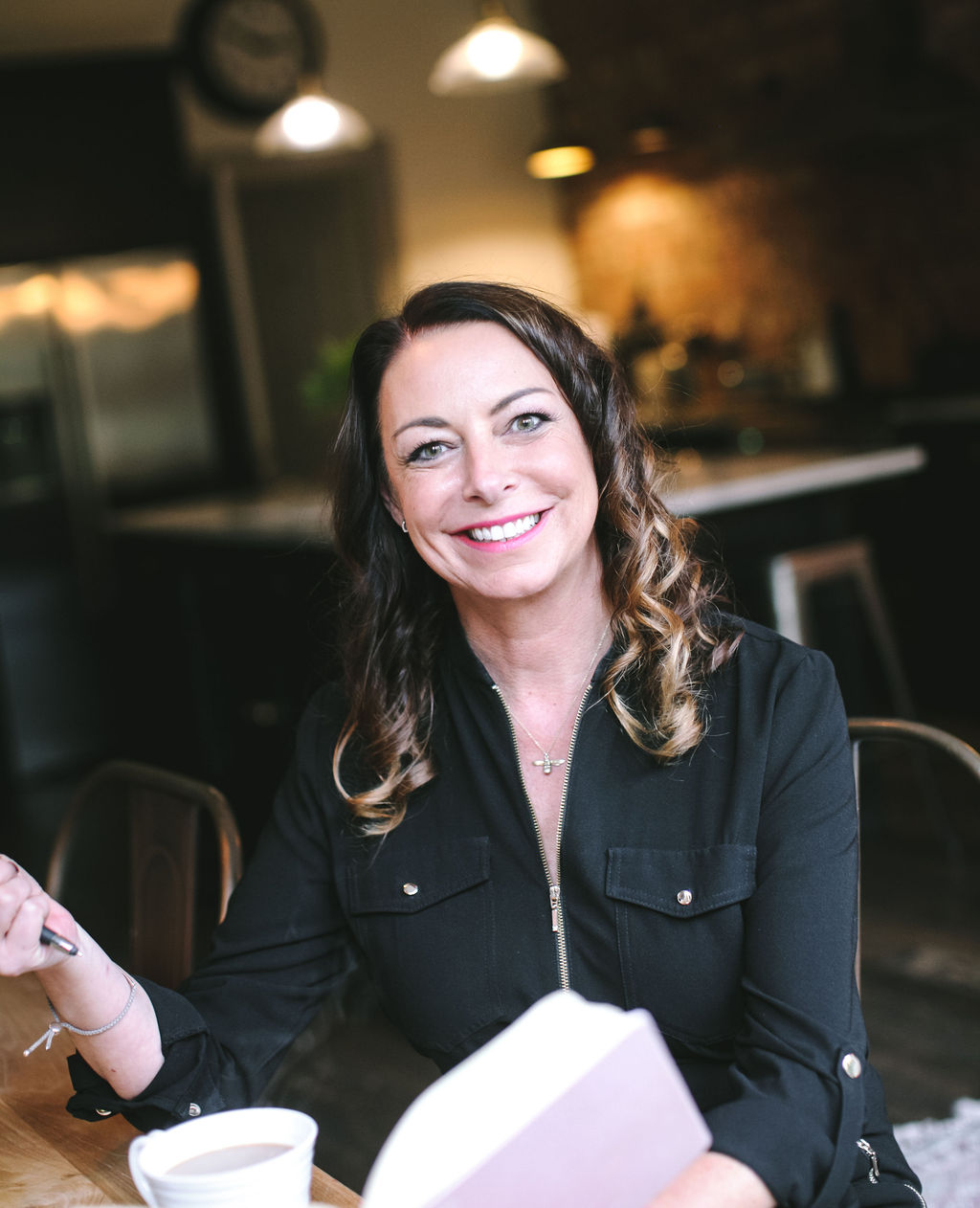 Amanda smiling warmly with notebook and coffee, ready for 1:1 coaching
