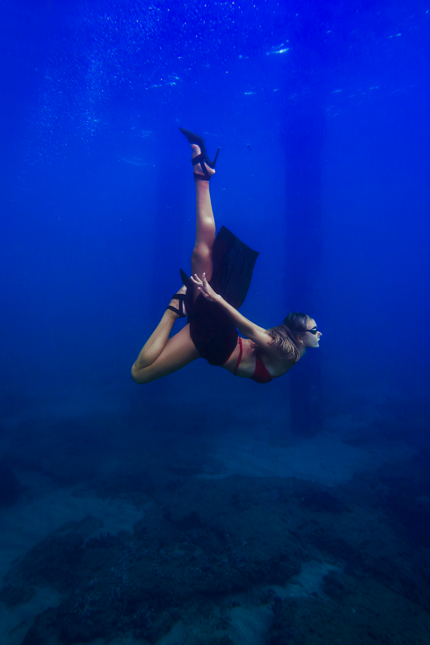 Kristina Makushenko diving gracefully underwater in high heels and swim attire