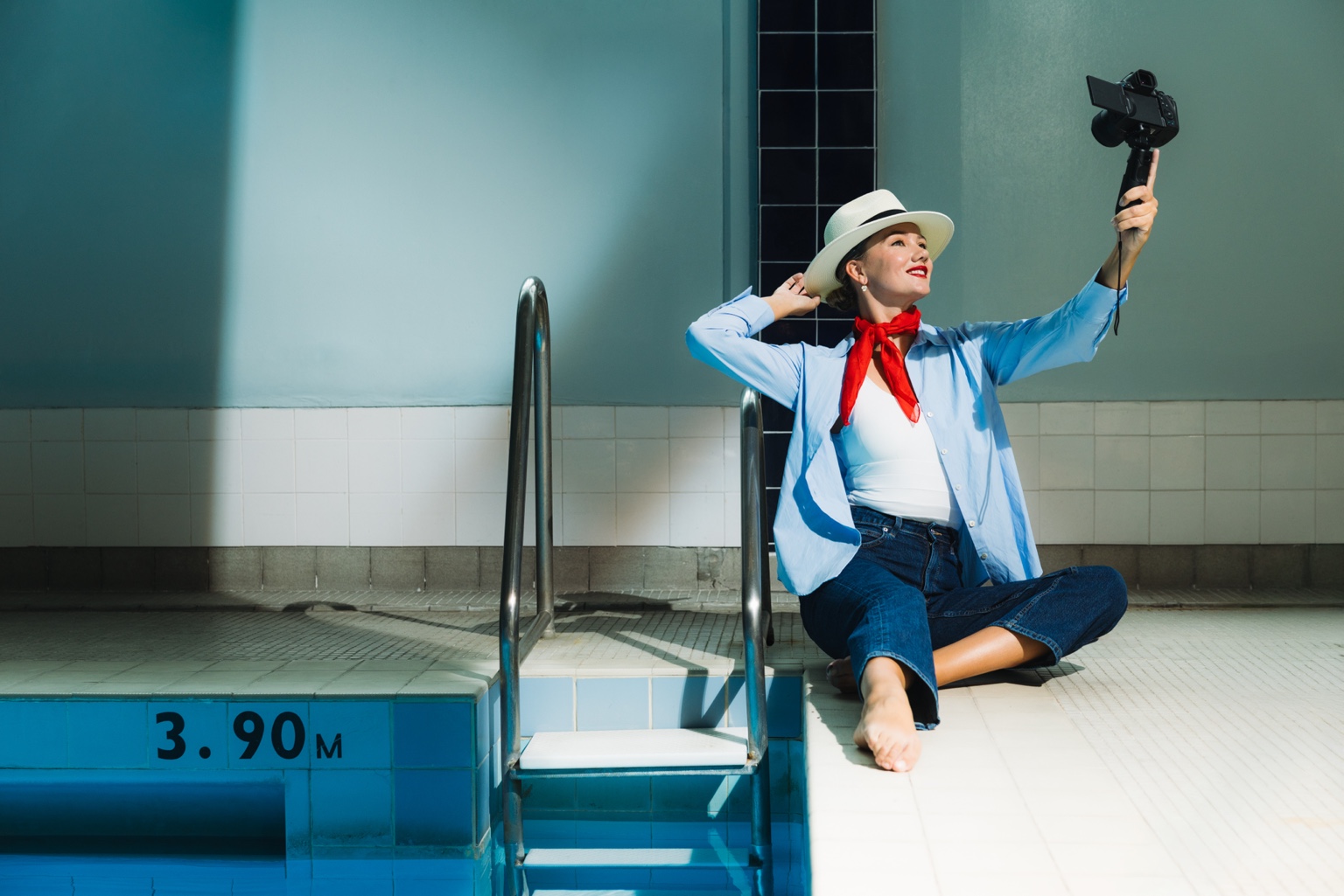 Kristina Makushenko sitting on pool steps holding a camera with a 3.90m depth marker
