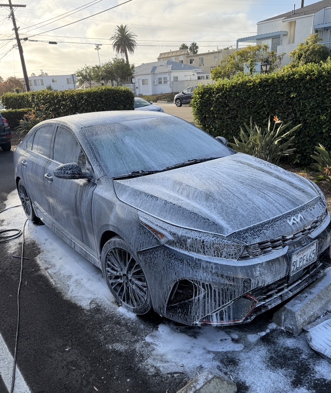 Kia sedan covered in thick snow foam during mobile exterior wash
