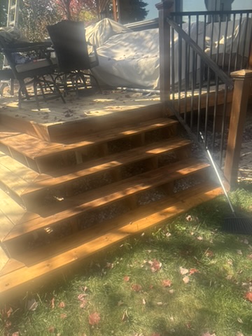 Custom deck stairs with warm wood stain and black metal balusters