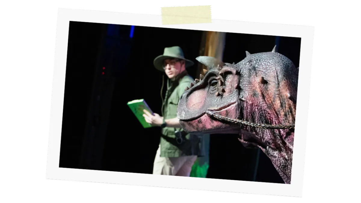 Ranger with field survival guidebook standing beside a dinosaur