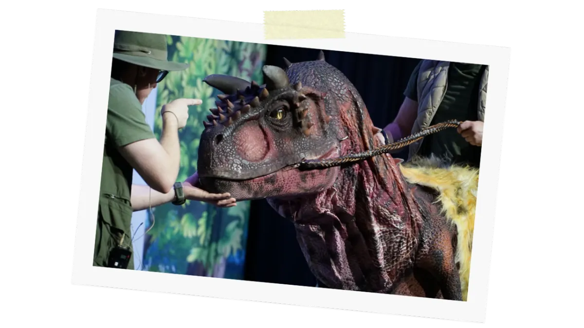 Ranger interacting with a horned Carnotaurus dinosaur on stage