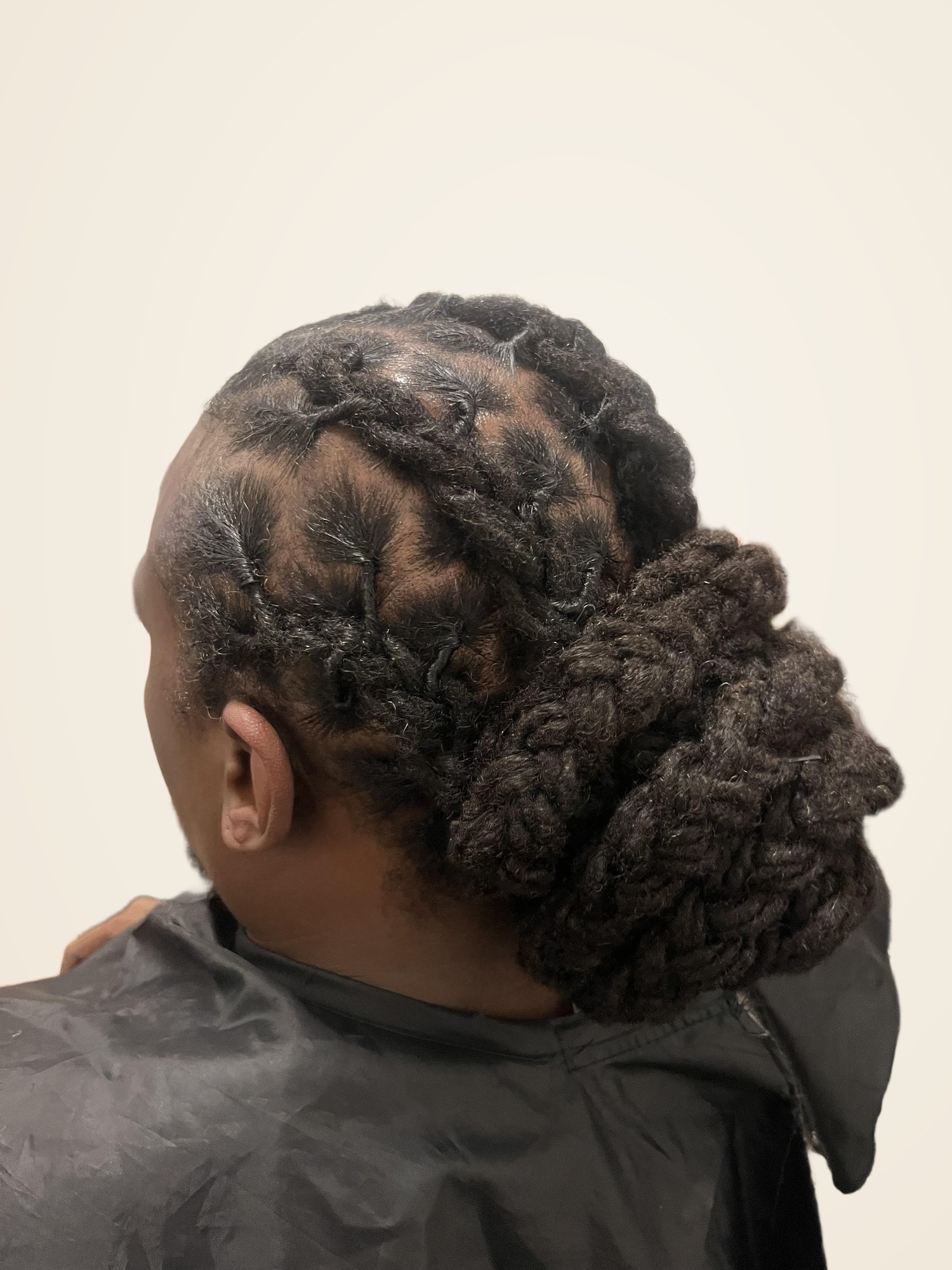 Detailed barrel-roll loc updo with low bun by Jennifer J at LOC & Curl Xpress ATL Salon in Decatur, GA