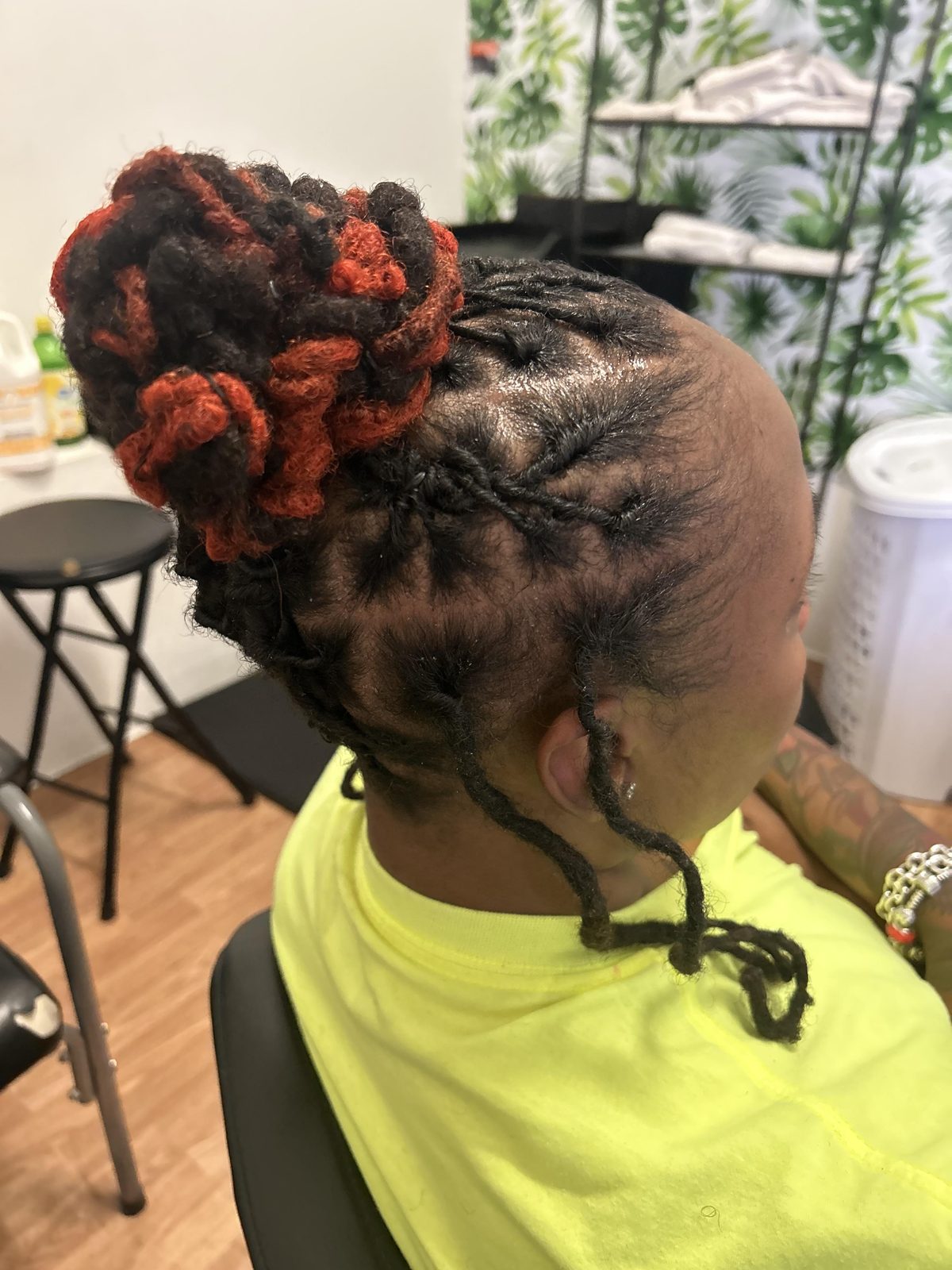 High bun loc updo with vibrant copper-red accent locs and detailed side flat-twists by Jennifer J at LOC & Curl Xpress ATL Salon in Decatur, GA