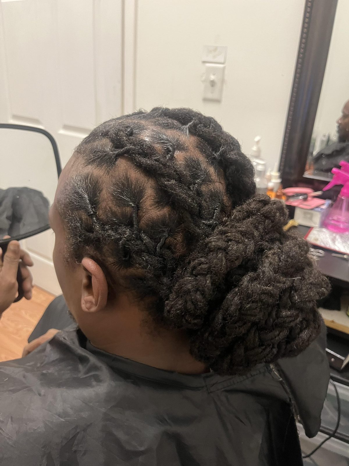 Detailed barrel-roll loc updo with low bun by Jennifer J at LOC & Curl Xpress ATL Salon in Decatur, GA