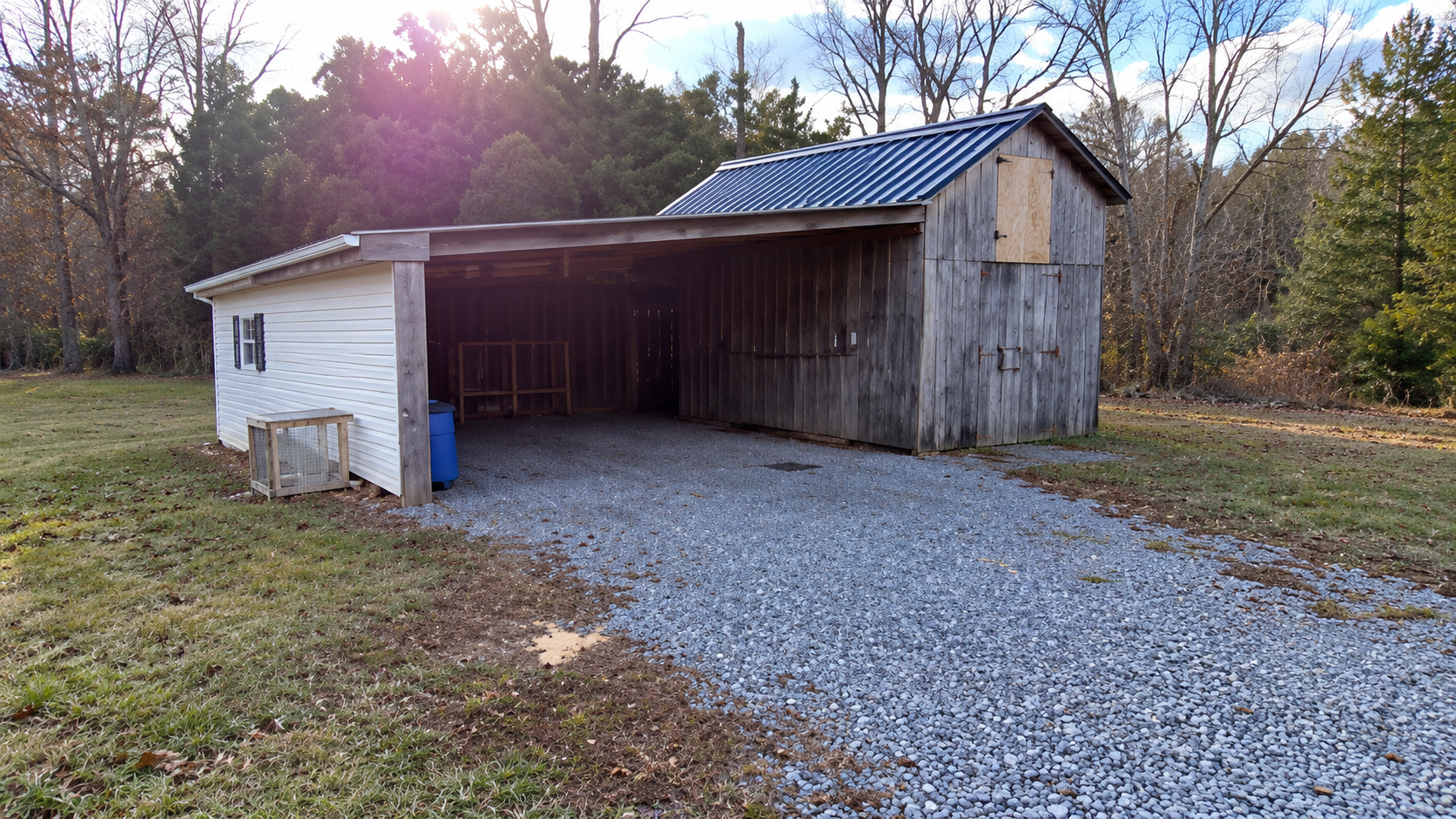 Detached open-style carport and barn structure with gravel driveway on level grounds