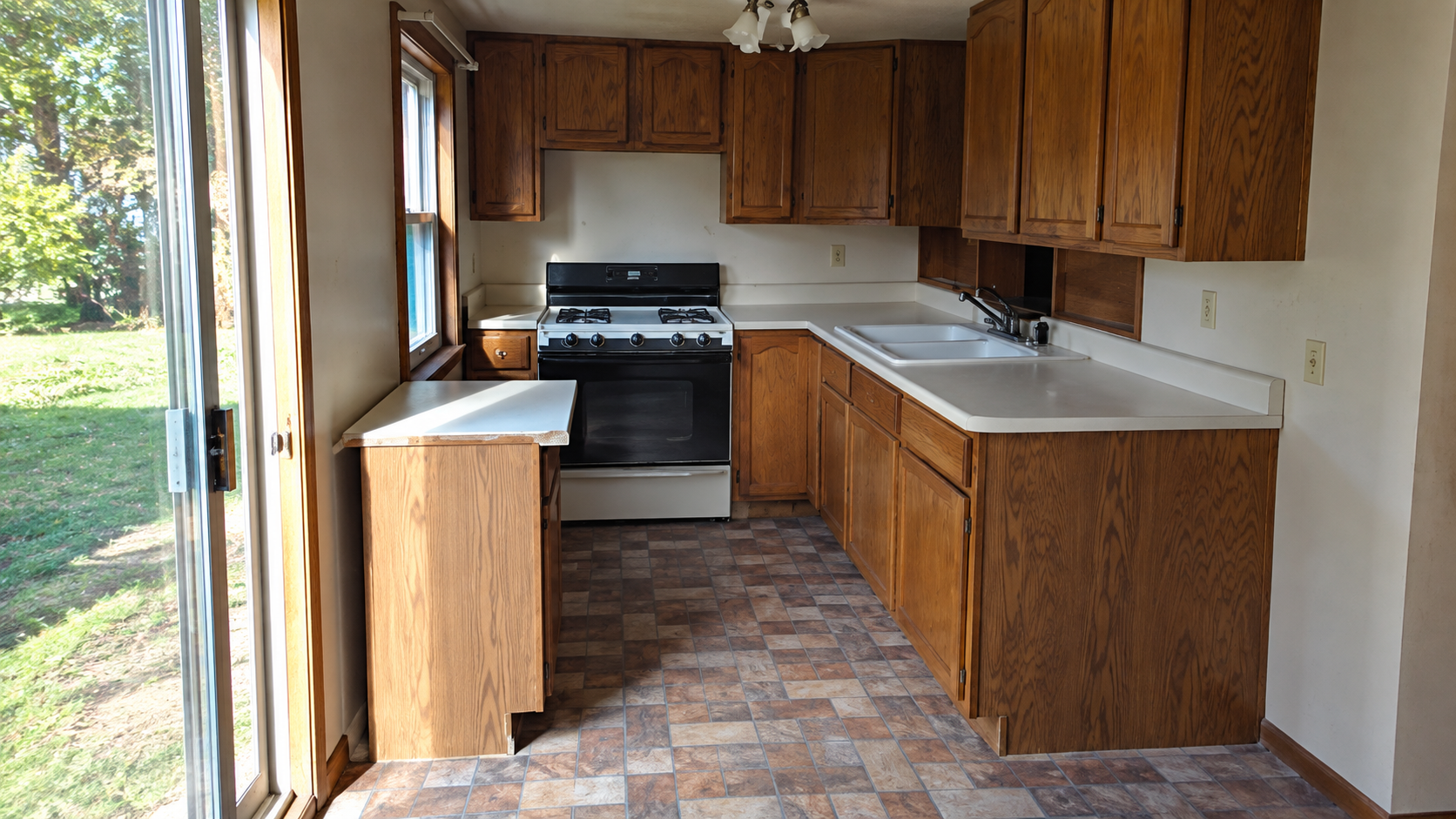 Dedicated second kitchen arrangement with oak cabinets, gas range, double sink, and sliding door to the yard