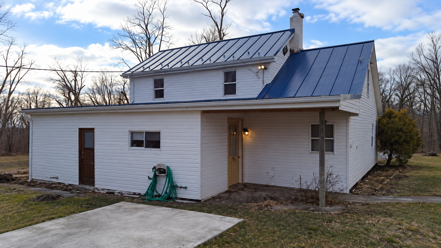 Side elevation showing covered porch entry, exterior coach lighting, and concrete apron