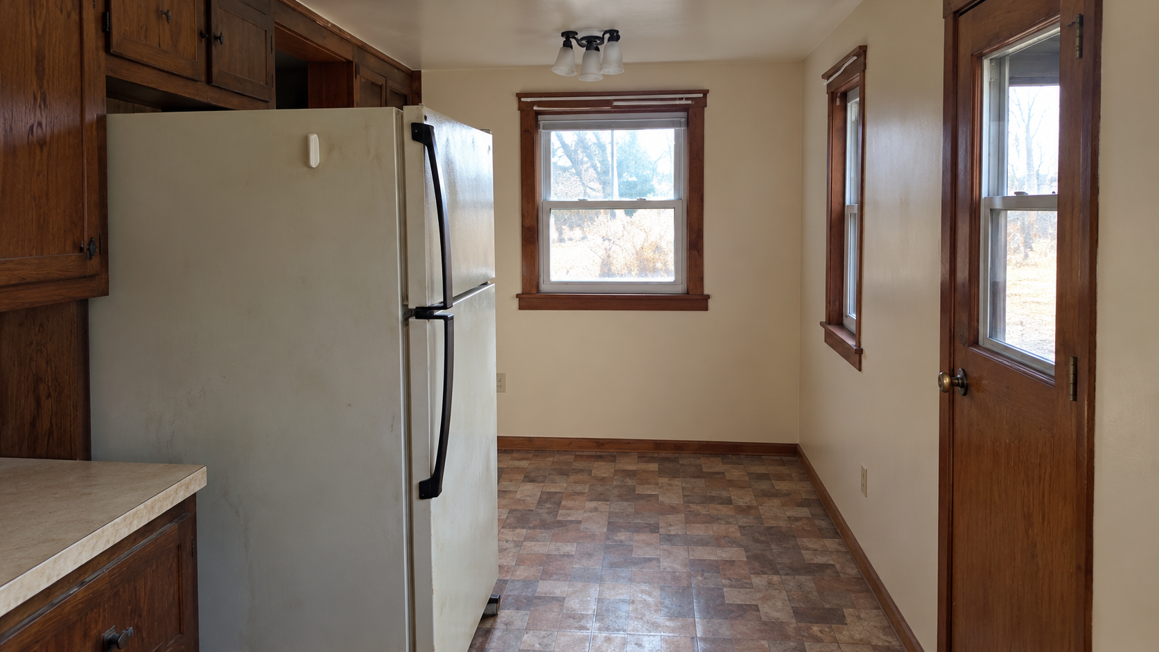 Kitchen refrigerator alcove, country wood trim windows, and exterior entryway door