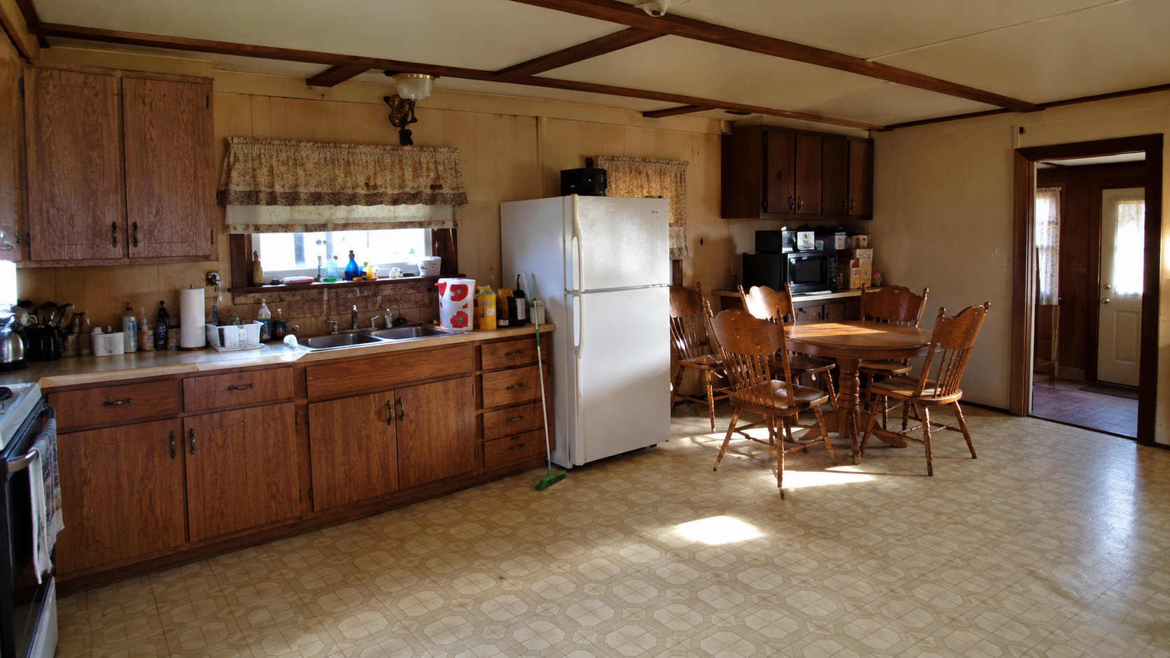 Spacious country kitchen and dining area with exposed dark ceiling beams and warm wood cabinetry