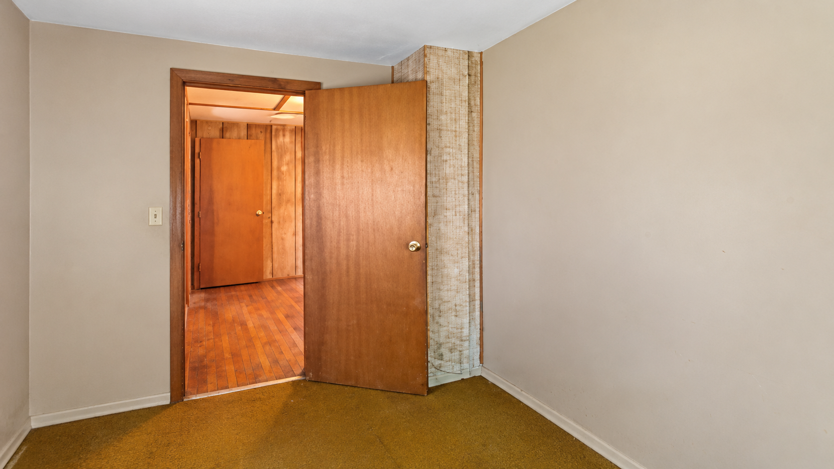 Interior doorway leading to adjacent bedroom suite with natural wood plank flooring