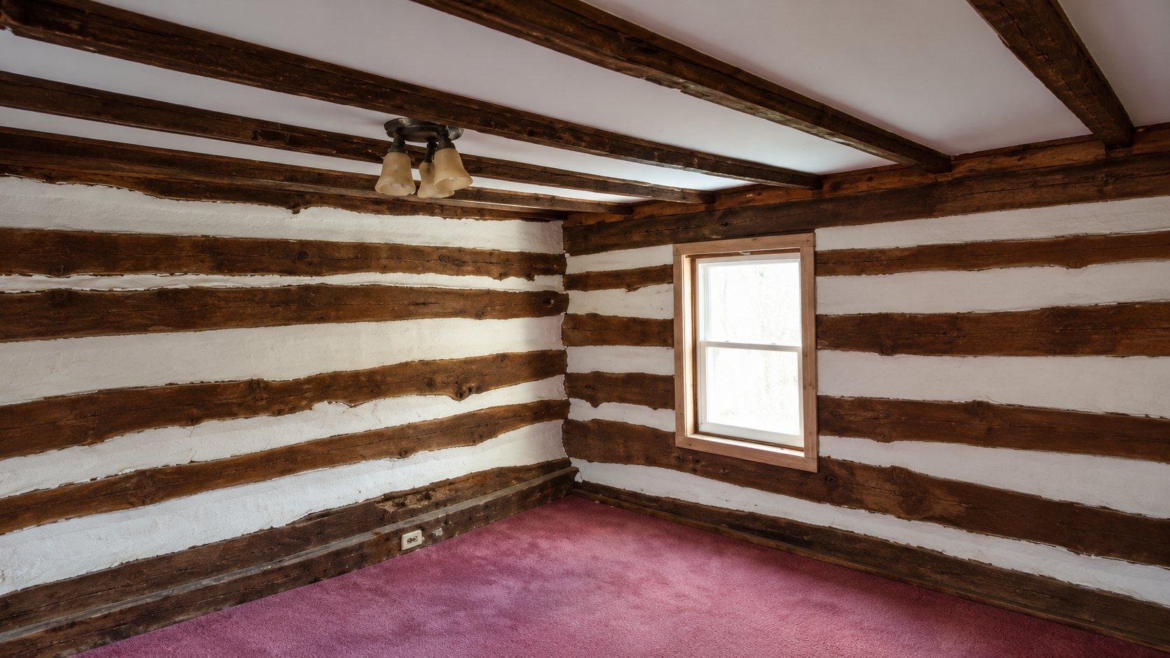 Interior room with exposed hand-hewn ceiling beams and authentic log and chinking walls