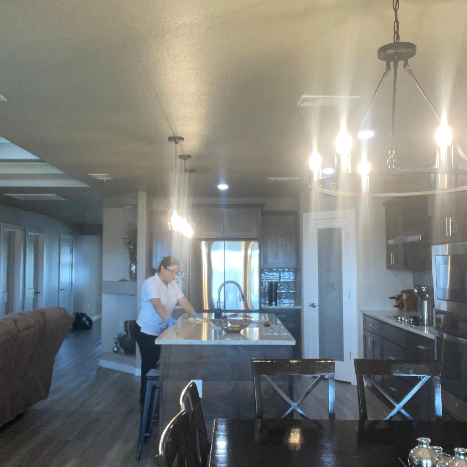 Cleaning contractor team sanitizing modern kitchen and chandelier dining room in Hobbs NM