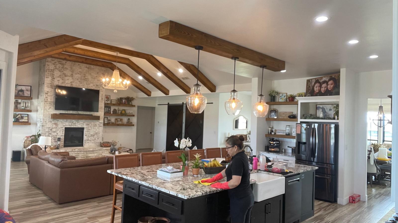 Cleaning specialist detailing large granite island in modern open-concept home in Hobbs NM