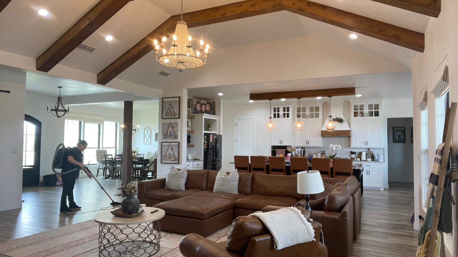 Adri's Cleaning Services team member vacuuming luxury open-concept living room with vaulted ceilings in Hobbs NM