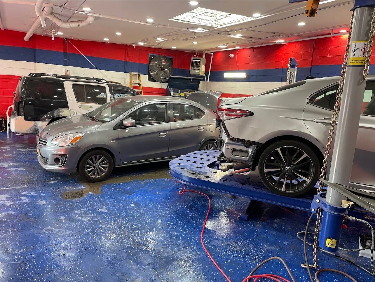 Repair bays and collision restoration frame lift inside Champs Auto shop