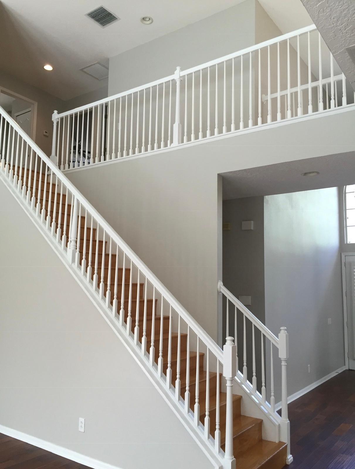 Two-story high foyer interior painting with crisp semi-gloss white staircase balusters and second-floor railing in Land O' Lakes FL