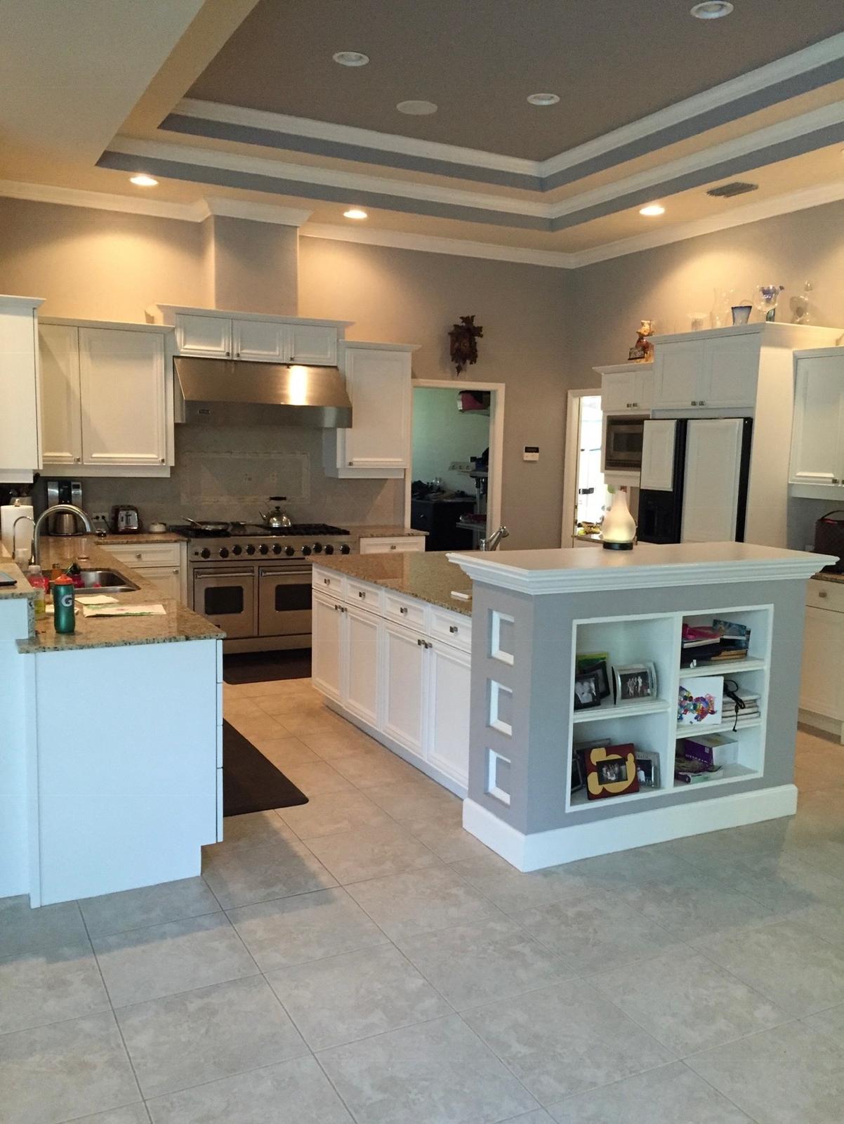 Completed kitchen cabinet spray painting in bright factory white with grey island accent and tray ceiling in Land O' Lakes FL