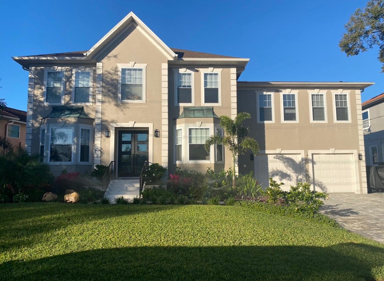 Grand two-story luxury residence complete exterior stucco painting and crisp white trim accents in Tampa FL