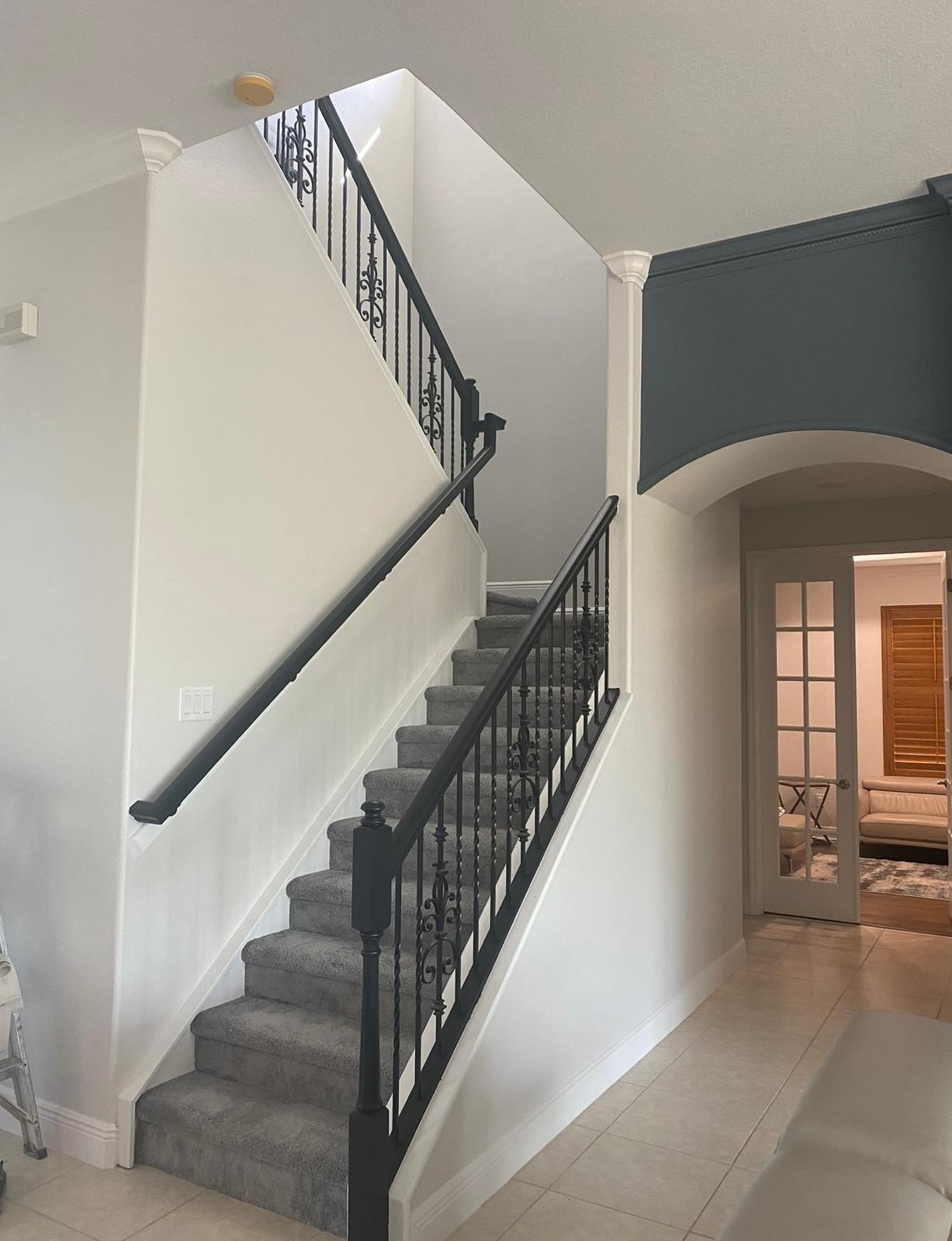 Interior high-foyer painting featuring flawless white walls, charcoal slate accent arch, and painted wrought iron stair rail in Wesley Chapel FL