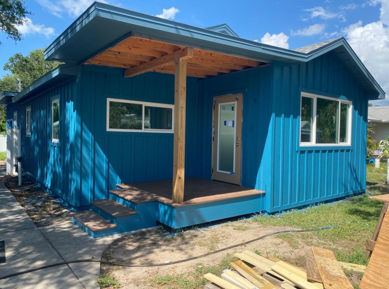 Board and batten coastal home painted in rich vibrant teal blue with natural cedar porch roof in Clearwater FL