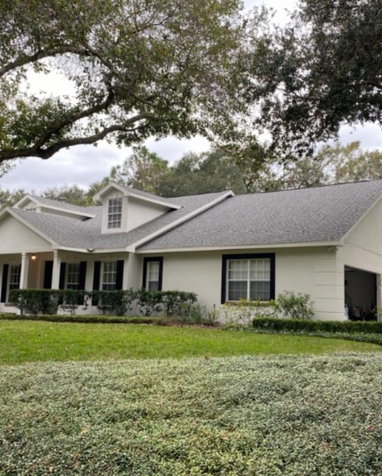 Completed exterior painting of single-story Florida ranch with crisp white siding and dark charcoal window trim in Land O' Lakes FL