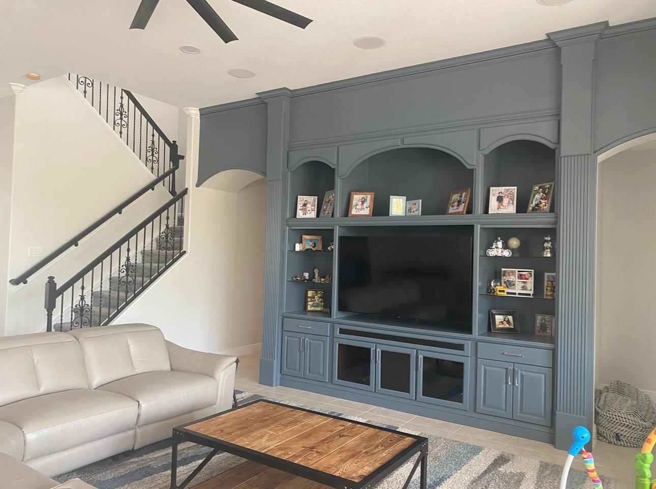 Finished custom entertainment center and wall unit painted in designer slate blue with fluted pilasters and arch accents in Wesley Chapel FL