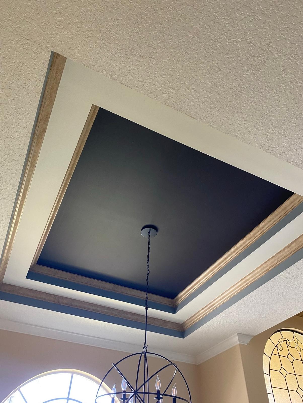 Custom architectural recessed tray ceiling painted in matte dark charcoal with stained wood moulding detail and pendant light fixture in Tampa Bay FL