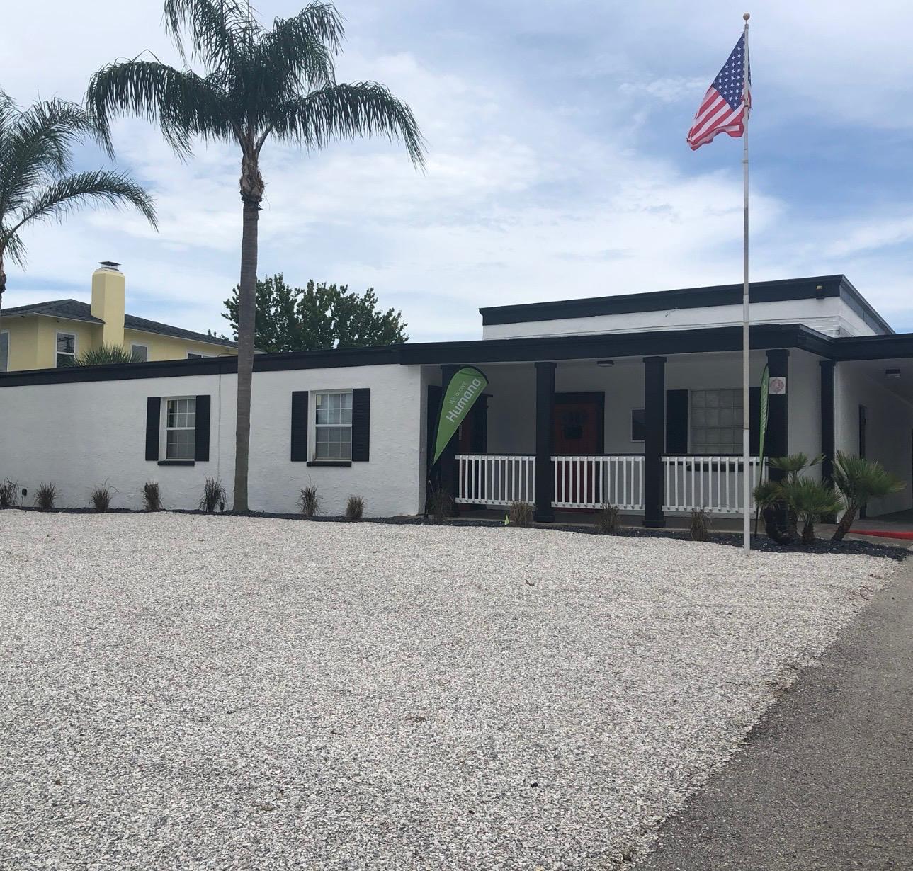 Commercial office building exterior painted in bright white stucco with modern black fascia, window shutters, and front veranda in Tampa Bay FL