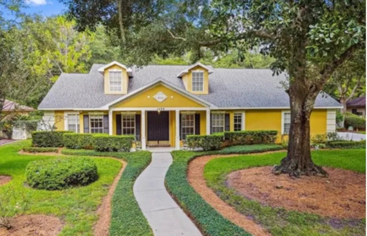 Beautiful Florida single-story ranch home painted in warm golden yellow with crisp white trim, shutters, and lush manicured lawn in Tampa Bay FL